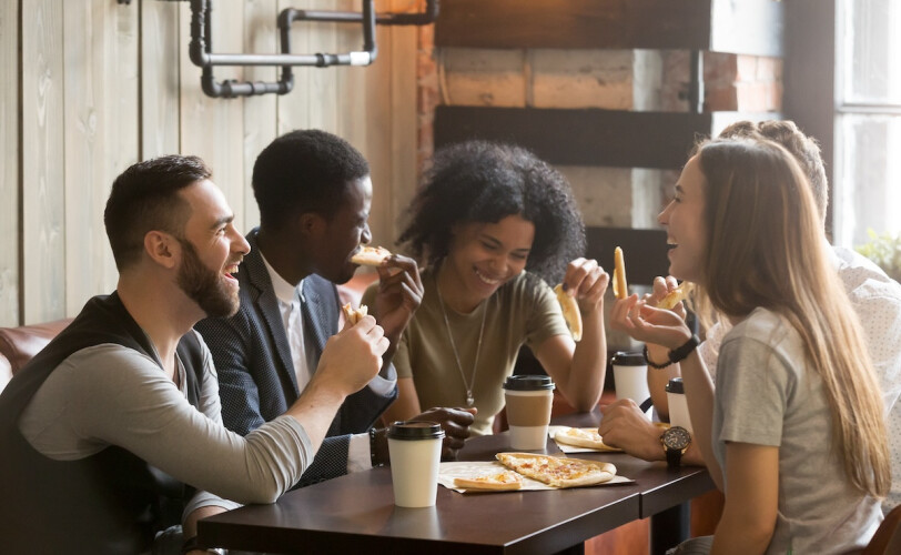 Junge Menschen teilen Pizza und Kaffee an einem Tisch im Café